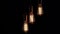 Three retro lamps hang and turn on at the same time on black background. Antique bulbs with old lamp holder are switched