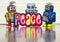 Three retro robot toys holding a bright and colorful cloth peace sighn