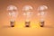 three retro style lightbulbs with glowing filament standing in a row on infinite colorful background creativity design concept