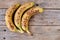 Three ripe bananas with spots on the skin on the rustic table
