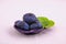 Three ripe blue plums on a small dish in studio