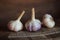 Three ripe heads of fresh garlic on a dark wooden background. Folk medicine for viral and colds