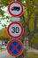 Three road signs on post against old trees. No Goods Vehicles Warning Sign, Speed limit sign and No Stopping sign