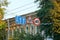 Three road signs on the wire against the background of branches with leaves and the walls of the building