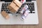 Three rolls of pound banknotes and a shopping cart with express boxes on the laptop keyboard