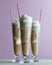 Three root beer floats made with vanilla ice cream and cherry garnish, topped with red paper straws with heart motif.