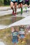 Three runners and their reflections visible in puddle