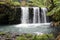 Three rushing waterfalls cascading over a volcanic hillside in a rainforest in Pua\\\'a Ka\\\'a Wayside Park, Haiku, Maui