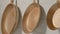 Three rustic copper fryingpans hanging on wooden white kitchen wall in restaurant or at home. Round empty gold or yellow