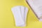 Three sanitary pads and an open pack on a yellow background