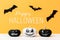 Three scary Black and White Jack o Lanterns and flying paper bats over yellow background. Halloween background.