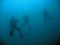 three scuba divers on deep dive