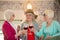 Three senior happy ladies having a party and looking enjoyed while drinking wine