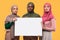 Three Serious Muslim Women Holding Blank Paper Board, Yellow Background