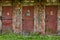 Three shabby steel doors, painted red on an abandoned warehouse.