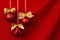 Three shimmer red balls with gold bows hang on ribbons in row on deep scarlet silky smooth wavy wall, closeup, copy space. Luxury.