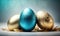 three shiny blue and gold easter eggs on a white surface with a feathery edge and a blue background with a blue and gold egg