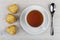 Three shortbread cookies, cup of tea on saucer, spoon