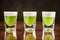 Three shot glasses of green alcoholic cocktails