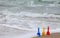 Three shovels in the beach sand with the ocean waves in the background