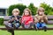 Three siblings sitting on bench and eating chocolate.