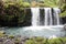 Three side by side, rushing waterfalls cascading over a volcanic hillside in a rainforest in Pua\\\'a Ka\\\'a Wayside Park