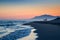 Three silhouettes of people stroll along the beach of Cabopino, Marbella, Malaga during sunset