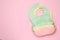 Three silicone baby bibs on pink background, top view. Space for text