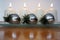 Three silver Christmas balls and four white Advent candles with flames