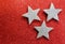 Three silver stars on bright red glittery illuminated background