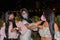 Three sisters colliding elbows and wearing protective masks in a park during the coronavirus pandemic