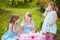 Three sisters playing tea party outdoors.