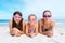 Three sisters on a seaside beach lying on their bellies in swimming goggles and swimwear
