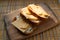 Three slices of hard cheese and butter sandwiches on oval bran bread, food on a wooden plank, breakfast and a snack