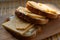 Three slices of hard cheese and butter sandwiches on oval bran bread, food on a wooden plank, breakfast and a snack