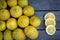 Three slices of  lemon along with a group of lemons on a wood table