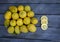 Three slices of  lemon arranged with a group of lemons on a wood table