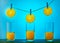 Three slices of orange hanging on a rope with clothespins and flowing orange juice in glasses on a blue background. Healthy eating