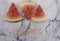 Three slices of watermelon on a marble background with the word yummy