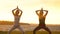 Three slim athletic girls in silhouette practicing a healthy lifestyle with yoga on the beach