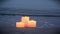 Three small candles on sandy beach near sea ocean waves burning