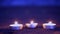 Three small candles tablets lie on a sandy beach near the waves