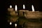 Three small flat candlesticks with burning white candles on a dark background in a dark room 2