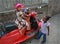 Three small girls playing near the african parked red scooter.