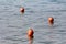 Three small orange buoys left by local fishermen floating on calm blue sea near shore