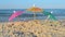 Three small paper cocktail umbrellas stand in sand on sandy beach close-up.