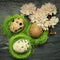 Three small quail eggs in side tiny green nests with relaxing fl