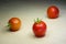 Three small red tomatoes lie on a light wooden background