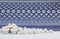 Three small white lit candles with white pebbles and indigo printed cloth background
