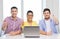 Three smiling colleagues with laptop in office